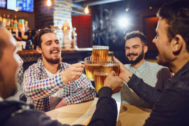 istock Friends clinking beer mugs in bar 1169127655
