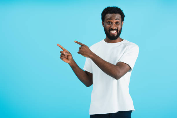 istock cheerful african american man pointing isolated on blue 1169130121