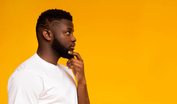 istock Profile portrait of thoughtful african man on yellow studio background 1169133630