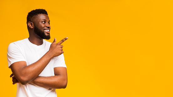 Look There. Excited Guy Pointing Finger Aside At Free Space For Text. Yellow Background