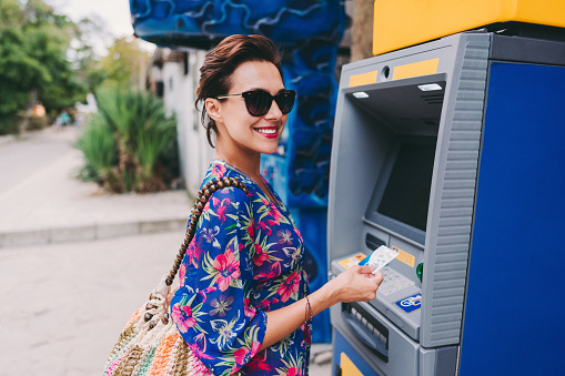 Woman on vacation withdrawing cash on the ATM