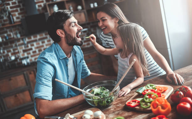 Family on kitchen Mom, dad and daughter are cooking on kitchen. Happy family concept. Handsome man, attractive young woman and their cute little daughter are making salad together. Healthy lifestyle. family dinners and cooking stock pictures, royalty-free photos & images