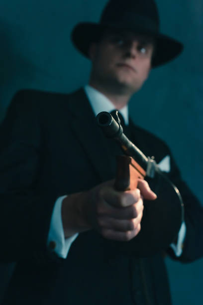 istock Retro gangster in hat shoots with machine gun. 1169137427