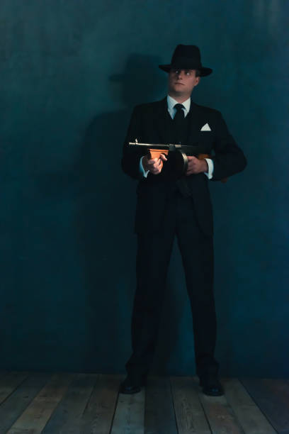 istock Retro gangster in hat shoots with machine gun. 1169137444