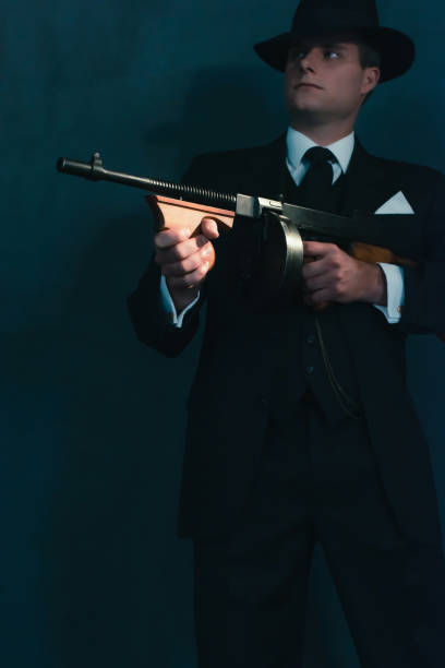 istock Retro gangster in hat shoots with machine gun. 1169137448