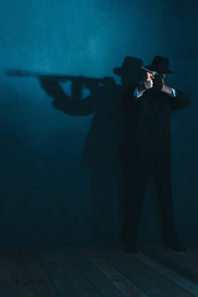 istock Retro gangster in hat shoots with machine gun. 1169137451