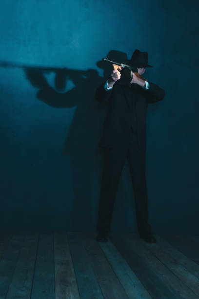 istock Retro gangster in hat shoots with machine gun. 1169137452