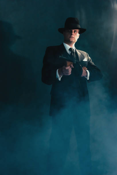 retro gangster in hat in misty night shoots with machine gun. - gun men spy suit imagens e fotografias de stock