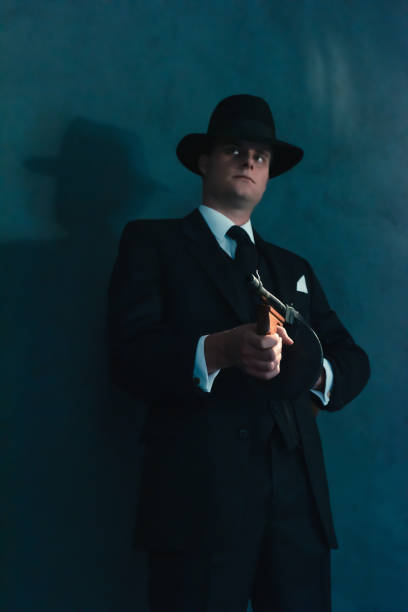 istock Retro gangster in hat shoots with machine gun. 1169137460