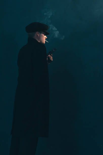 retro mobster with cigarette holds gun. side view. - handgun gun blue black imagens e fotografias de stock