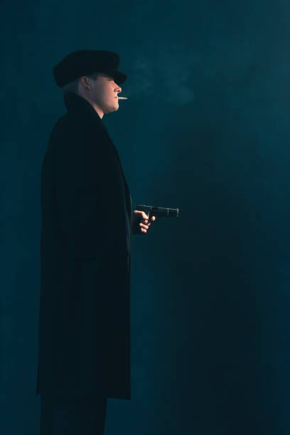 retro mobster with cigarette shoots with gun. side view. - handgun gun blue black imagens e fotografias de stock
