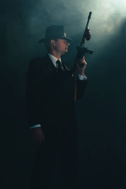 istock Retro gangster stands with machine gun in mist. 1169137744