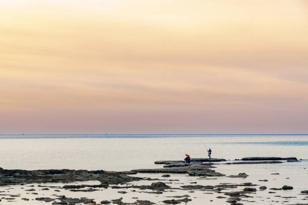 un hombre pescando al atardecer en trípoli líbano el 5 de febrero de 2018 - tripoli fotografías e imágenes de stock