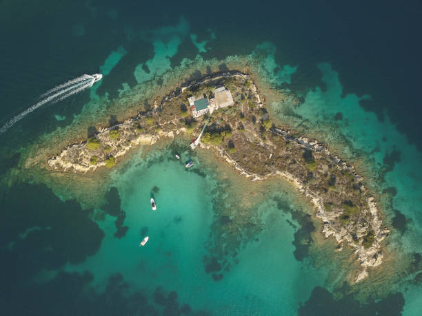 halkidiki, grecia : barche e yacht ormeggiati vicino all'isola privata in una posizione appartata sul mar egeo. vista dal drone - vacations halkidiki beach sand foto e immagini stock