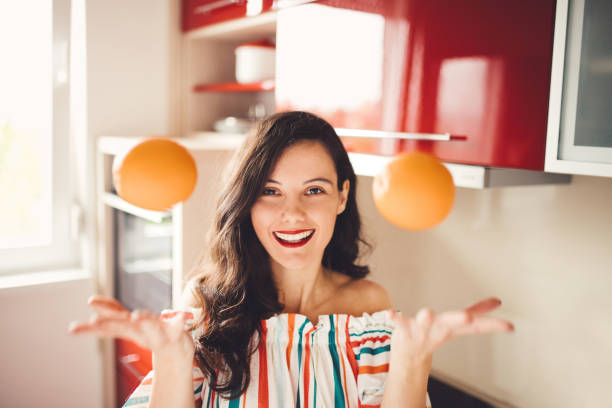 donna con arance in cucina - women mature adult smiling cheerful foto e immagini stock