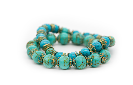 Bracelet made of blue turquoise stone on a white background, close-up, selective focus.