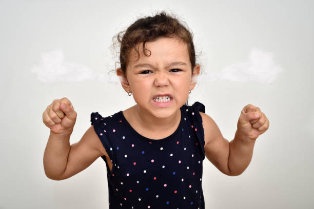 Angry and aggressive young girl with steam blowing out of her ears Angry and aggressive young girl with clenched teeth and fists and steam blowing out of her ears looking at the camera. Childhood and expressions concept. clenching teeth stock pictures, royalty-free photos & images