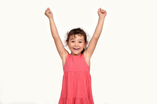 Happy and smiling cute young girl with hands up looking at the camera. Childhood and expressions concept.