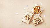 Gift or present boxes and stars confetti on golden table top view. Flat lay for birthday, christmas or wedding.
