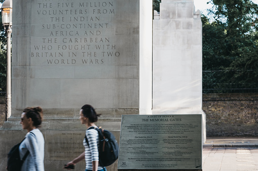 London, UK - July 15, 2019: People walking past The Memorial Gates, also known as Commonwealth Memorial Gates, a war memorial located at the end of Constitution Hill in London.