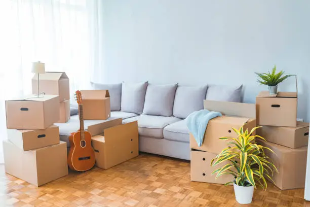 Moving day concept, cardboard carton boxes stack with household belongings in modern house living room, packed containers on floor in new home, relocation, renovation, removals and delivery service