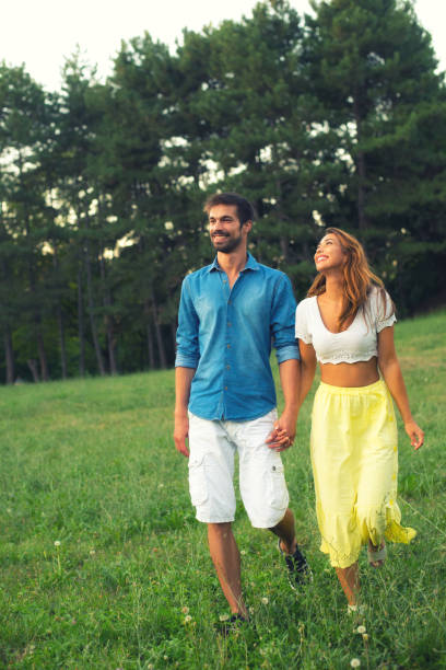 couple walking through the field and holding hands over sunset