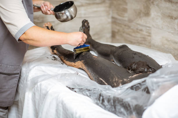 Man during a mud wrapping Man during a mud wrapping with special black mud, lying in the spa salon, worker applying mud on the legs people covered in mud stock pictures, royalty-free photos & images