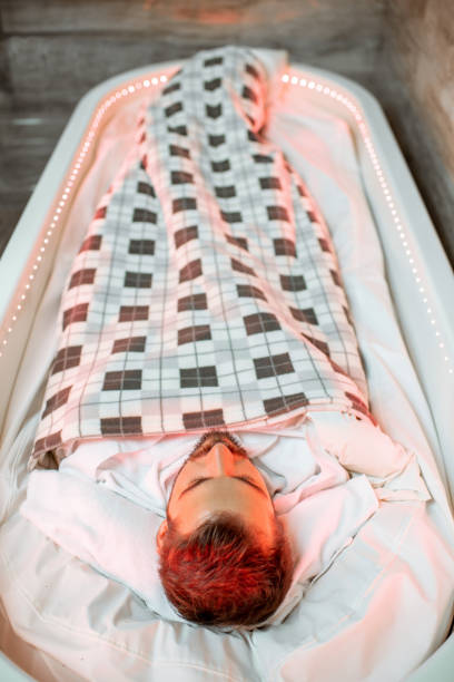 Wrapped man lying in the spa capsule Man lying in the hot SPA capsule wrapped with bedcover during the mud wrap procedure in the SPA salon people covered in mud stock pictures, royalty-free photos & images