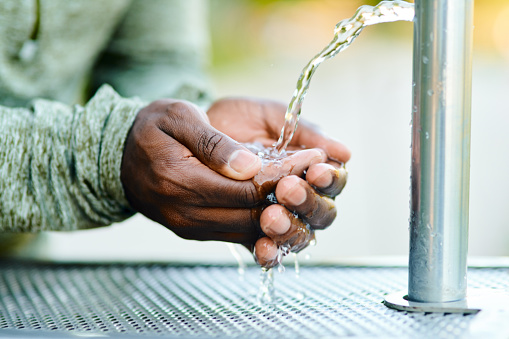Cropped shot of a man drinking water from a public park fountain