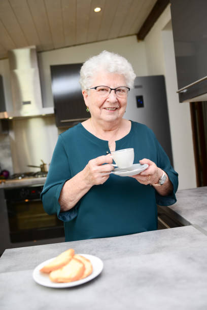 istock happy senior active woman drinking coffee in a modern kitchen at home 1169154121