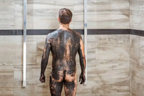 Man preparing for the high pressure shower after the mud wrapping procedure at the luxury SPA salon
