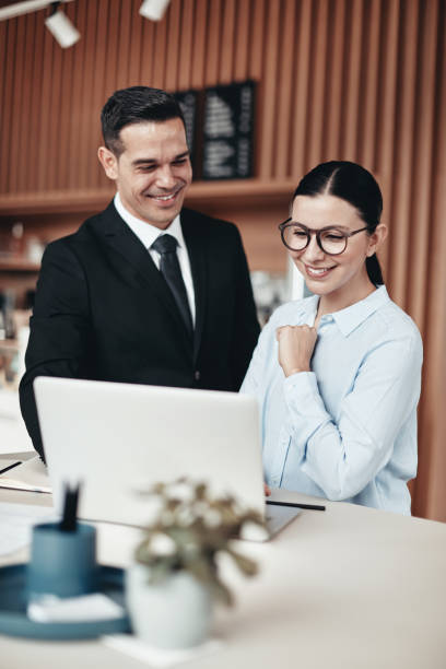 istock Two smiling businesspeople using a laptop together in an office 1169155730
