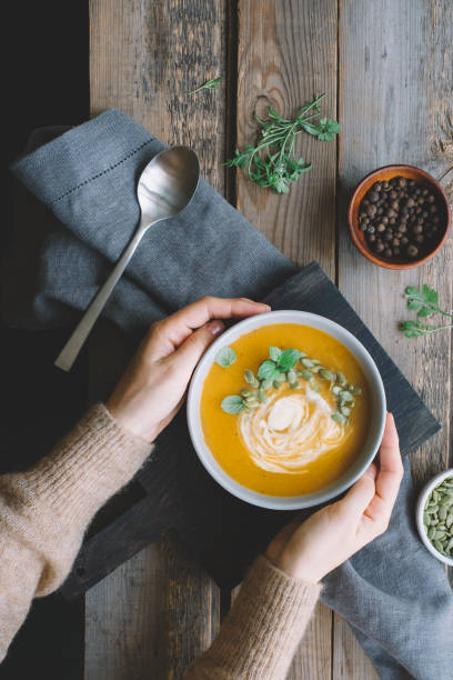 istock Female hands holding pumpkin soup 1169157122