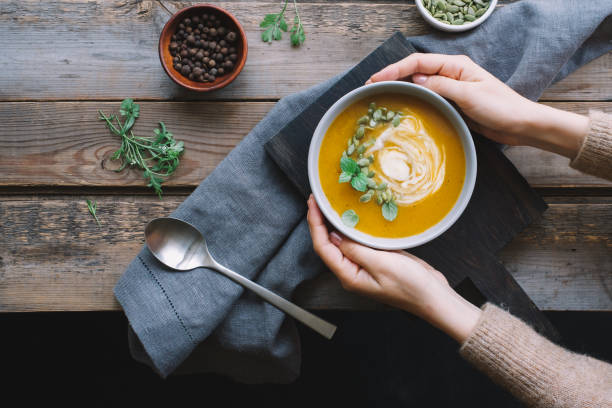istock Female hands holding pumpkin soup 1169157267