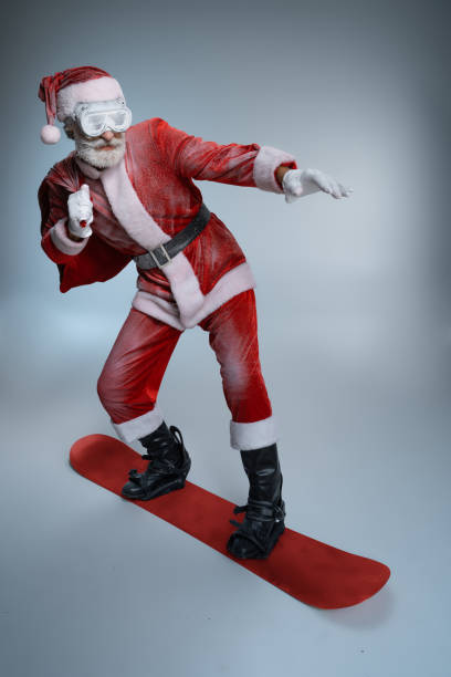istock Senior Santa Claus holding sack, standing on snowboard 1169157786