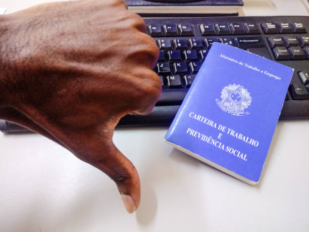 istock Man's hand making unpositive sign (thumb down) with Brazilian document work and social security and keyboard in the background 1169158936