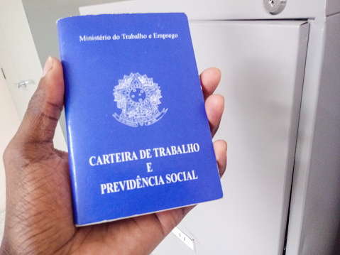 Black man holding a Brazilian document work and social security, in Portuguese: Carteira de Trabalho e Previdencia Social