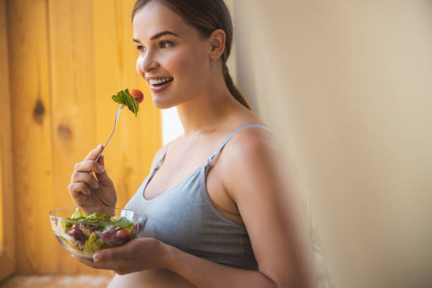 istock Joyful young woman eating fresh vegetable salad 1169163631