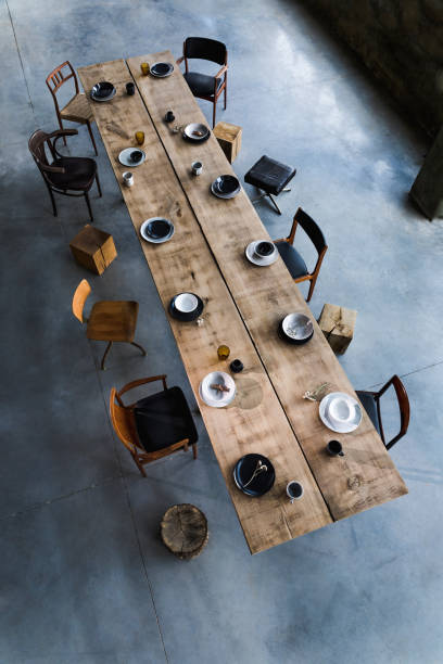 Design craft oak table with plates, bowls, cups and elegant accessories. Cement floor. Stylish and modern interior design of conference room. Template. elegante y moderno diseño interior de la sala de conferencias con mesa de roble de diseño, una gran cantidad de sillas retro, cubos de madera, platos y accesorios elegantes. suelo de cemento. plantilla. espacio abierto de oficina. vista superior.