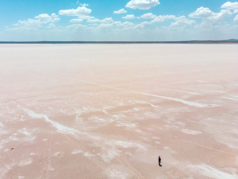 Aerial view of Lake Tuz, Tuz Golu. Salt Lake. White salt water. It is the second largest lake in Turkey and one of the largest hypersaline lakes in the world. It is located in the Central Anatolia Region, Ankara, Aksaray, Konya. A girl standing in the middle of the salt lake.