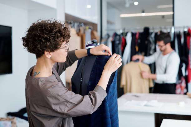 istock Young professional clothes designer working over unfinished dress on dummy 1169167636