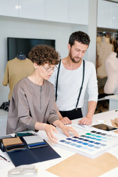istock Two young colleagues discussing color swatches by workplace 1169167667