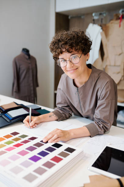 istock Young designer making notes and looking through catalogue of textile samples 1169167710