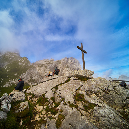Garmisch-Partenkirchen, Germany, August 8., 2019: Tourists admire the Alpspitze mountains in Werdenfelser Land next to a simple wooden puritanical cross.