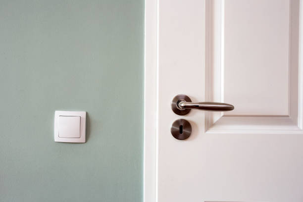 Modern white door with chrome door handle and light switch, new clean design