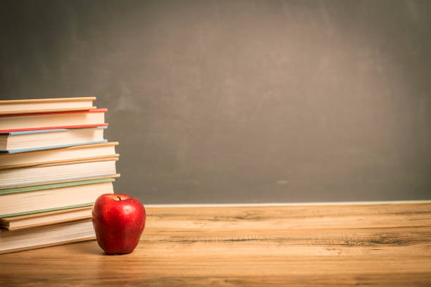 istock Textbooks on wooden school desk with chalkboard. 1169174156