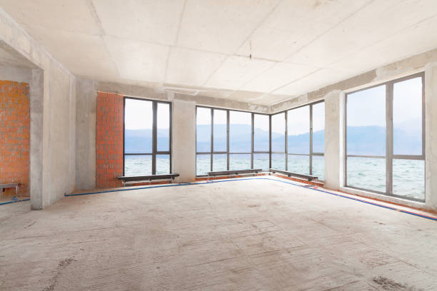 Construction site of residential apartment building interior in progress with large panoramic windows with sea view and orange brick wall. stock photo
