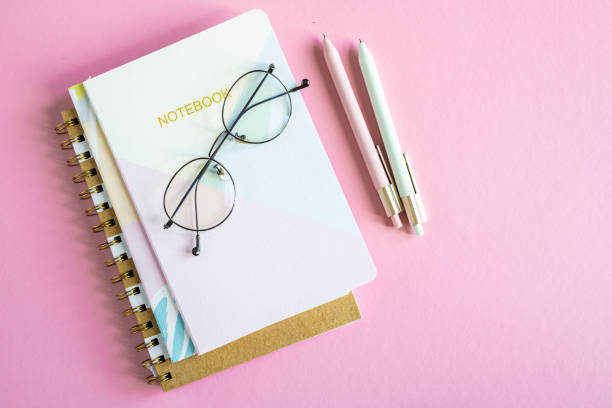 descripción general de la mesa rosa con pila de cuadernos, anteojos y dos bolígrafos - spiral notebook spiral ring binder blank fotografías e imágenes de stock