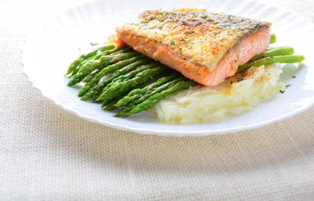 istock Grilled salmon garnished with asparagus and herbs and mashed potatoes, served on white plated.