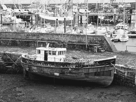 Black and white image of a derelict  boat in the harbour